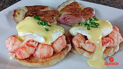 A photograph of langostino eggs benedict with smashed potatoes.
